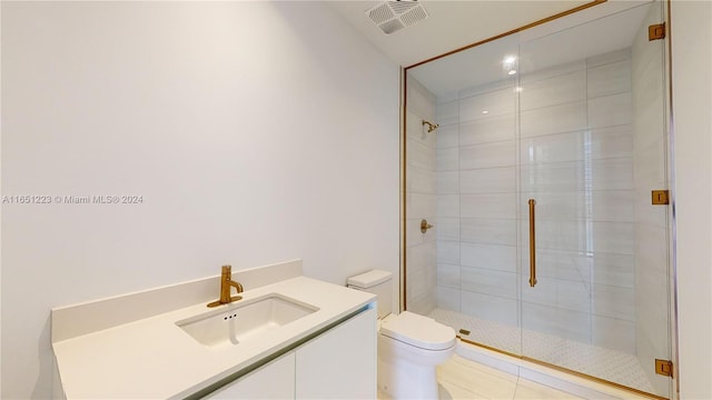 bathroom with a shower with door, vanity, toilet, and tile patterned flooring