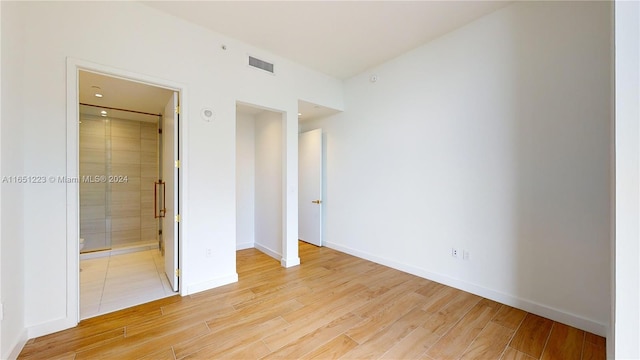 unfurnished bedroom featuring connected bathroom and light hardwood / wood-style floors