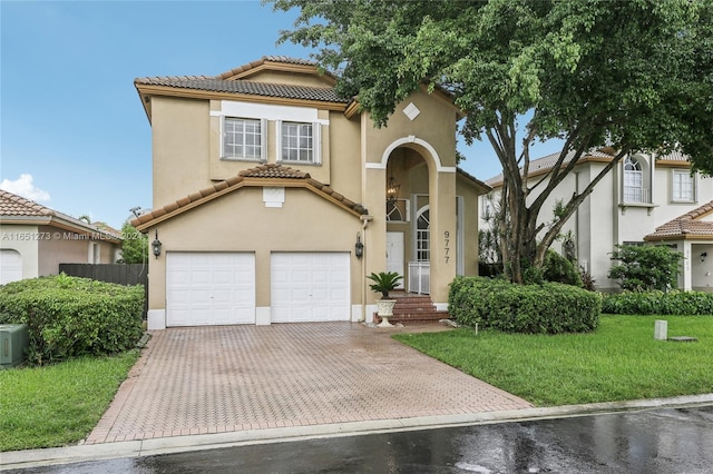 mediterranean / spanish home featuring a garage and a front yard