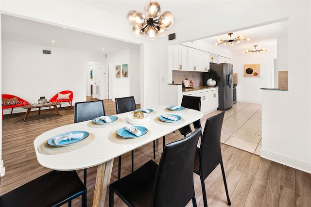 dining space with a chandelier, light hardwood / wood-style floors, and ornamental molding