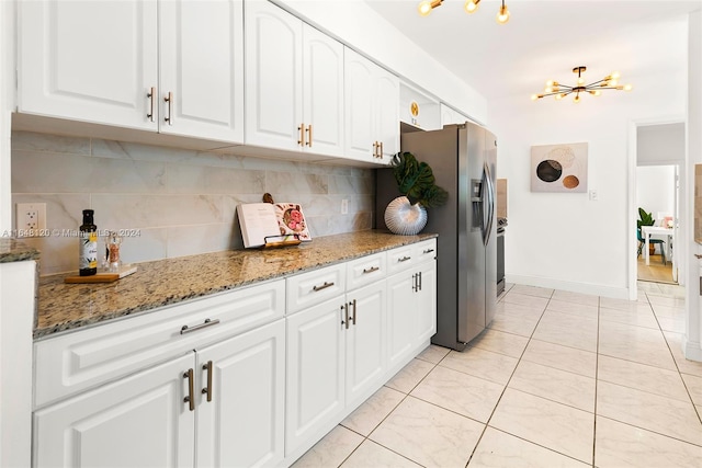 kitchen with light stone countertops, backsplash, white cabinets, and stainless steel refrigerator with ice dispenser