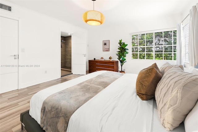 bedroom with ornamental molding and light hardwood / wood-style flooring