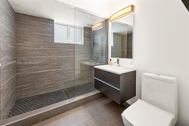 bathroom featuring vanity, toilet, tile patterned floors, and a tile shower