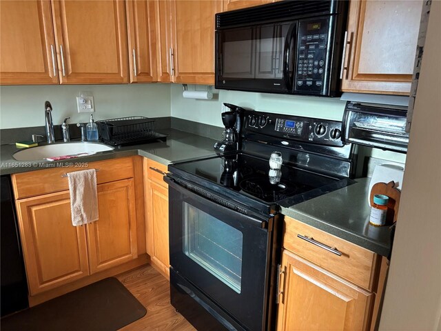 700 Layne Blvd Unit 212, Hallandale Beach, FL 33009 - kitchen with black appliances, a sink, dark countertops, and light wood-style floors
