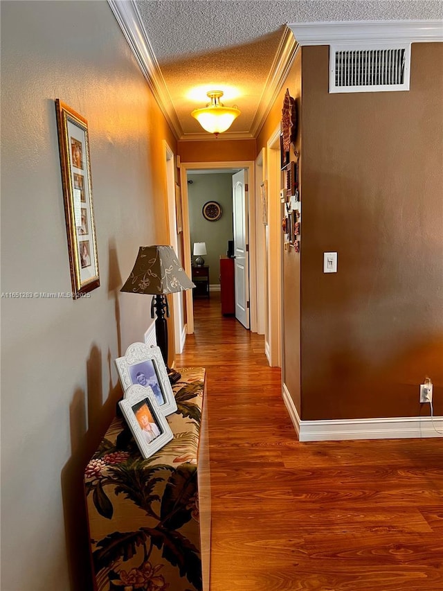 hall featuring hardwood / wood-style floors, ornamental molding, and a textured ceiling