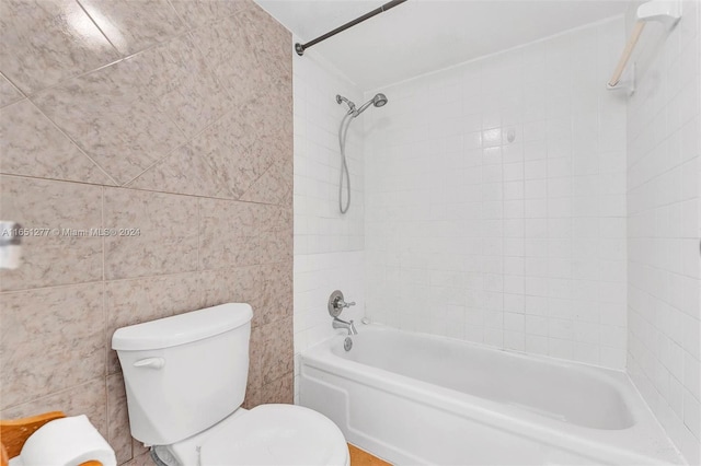 bathroom with tile walls, toilet, and tiled shower / bath combo