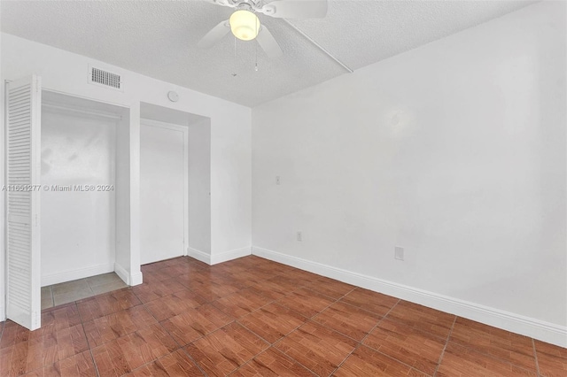 unfurnished bedroom with a textured ceiling, hardwood / wood-style floors, ceiling fan, and a closet