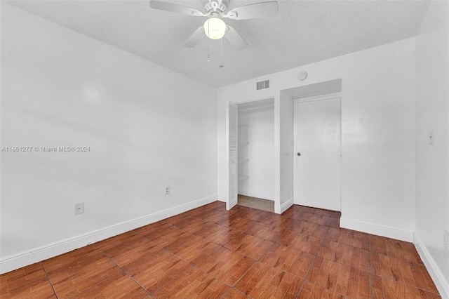 unfurnished bedroom featuring a textured ceiling, ceiling fan, hardwood / wood-style floors, and a closet