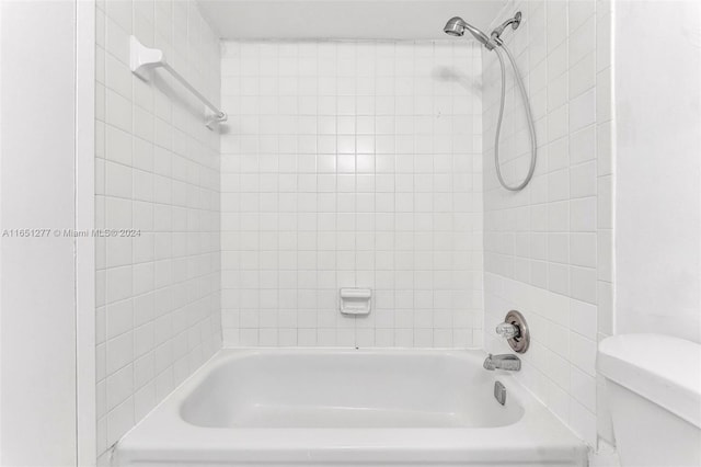 bathroom with toilet and tiled shower / bath combo