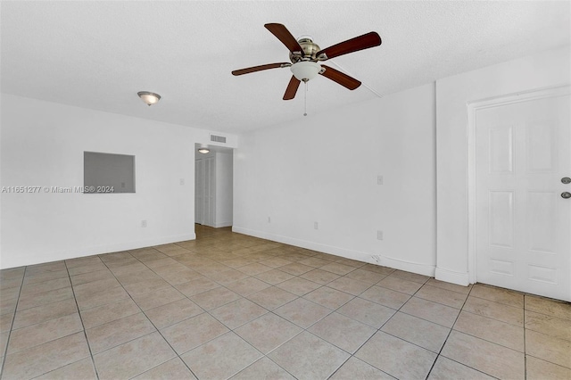 spare room featuring a textured ceiling, light tile patterned flooring, and ceiling fan