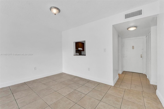 tiled empty room featuring a textured ceiling