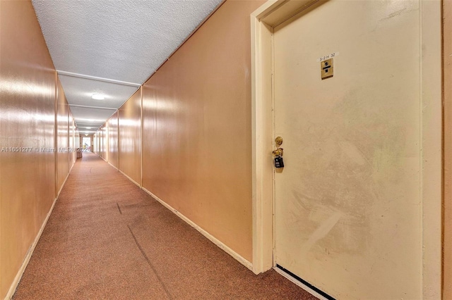 hall with a textured ceiling and carpet floors