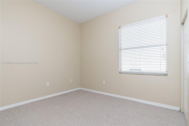 carpeted spare room with a textured ceiling