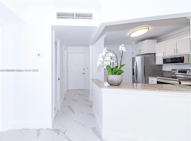 kitchen featuring ornamental molding, light stone countertops, appliances with stainless steel finishes, and white cabinetry