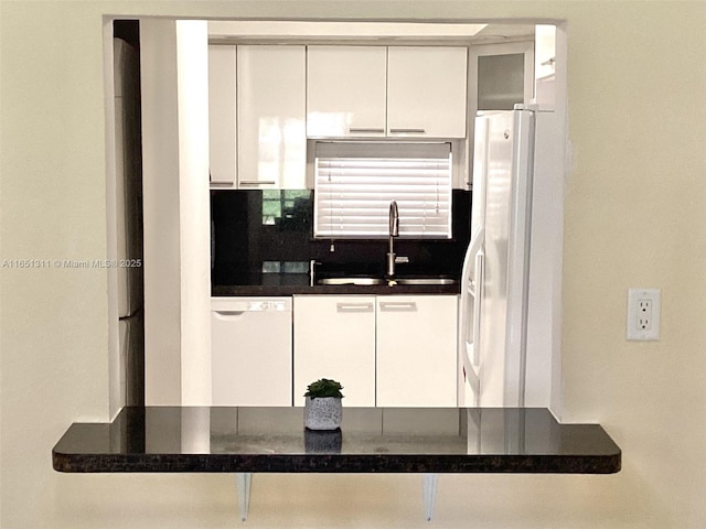 611 S Hollybrook Dr Unit 102, Pembroke Pines, FL 33025 - kitchen featuring white appliances, a sink, backsplash, white cabinetry, and dark countertops