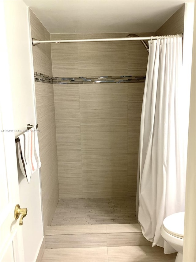 bathroom with toilet and a shower with shower curtain