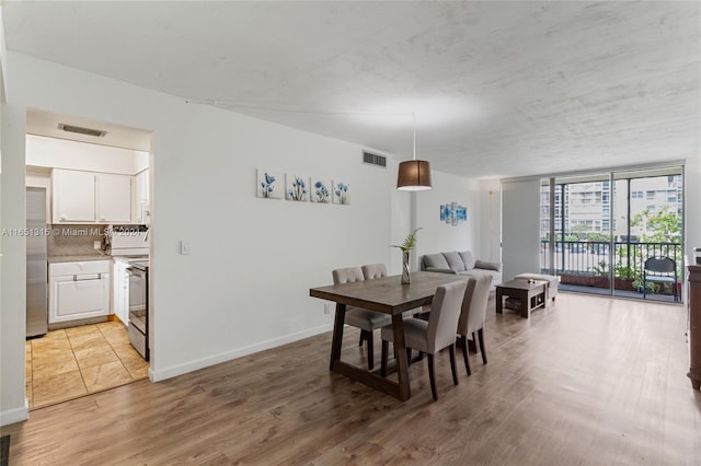 dining area featuring expansive windows and light hardwood / wood-style flooring