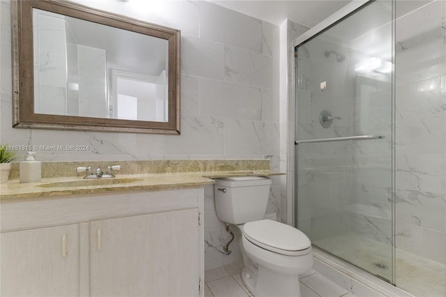 bathroom featuring toilet, tile walls, vanity, and a shower with shower door