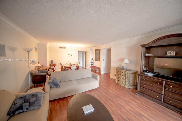 living room with visible vents, baseboards, ornamental molding, a textured ceiling, and light wood-type flooring