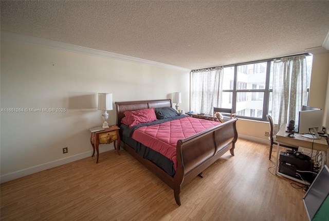 bedroom with crown molding, baseboards, light wood-type flooring, and a textured ceiling