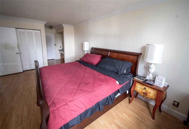 bedroom with a closet, a textured ceiling, wood finished floors, and ornamental molding