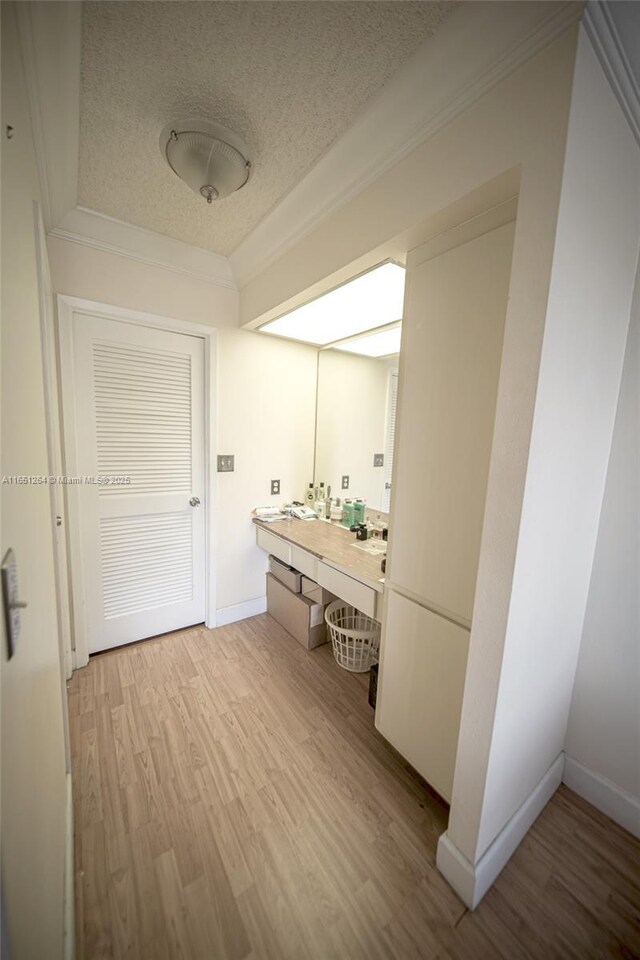 bathroom with hardwood / wood-style floors, ornamental molding, and a textured ceiling