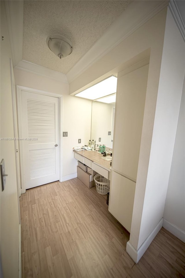 bathroom featuring ornamental molding, a textured ceiling, wood finished floors, baseboards, and vanity