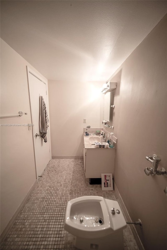 half bath with baseboards, vanity, and tile patterned flooring