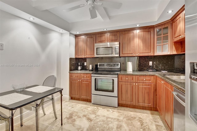 kitchen featuring stainless steel appliances, dark stone counters, backsplash, and ceiling fan