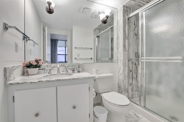 bathroom featuring vanity, a shower with shower door, and toilet