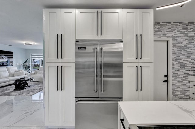 kitchen featuring white cabinetry, stainless steel built in refrigerator, and light stone countertops