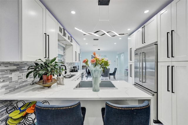 kitchen with built in fridge, light stone counters, and white cabinets