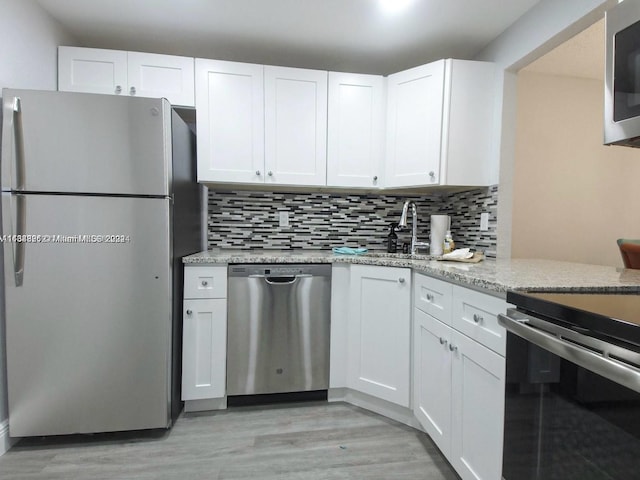 kitchen with appliances with stainless steel finishes, light stone countertops, and white cabinets