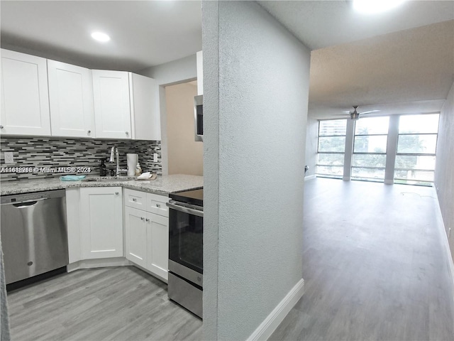 kitchen with appliances with stainless steel finishes, light hardwood / wood-style floors, white cabinetry, sink, and ceiling fan