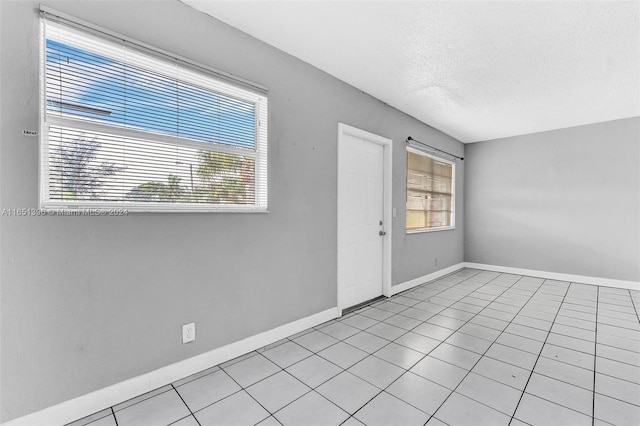 unfurnished room with light tile patterned floors, a textured ceiling, and a healthy amount of sunlight