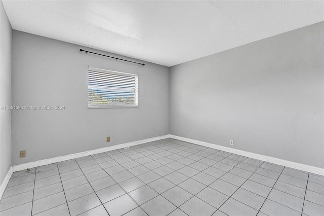 tiled spare room featuring a textured ceiling