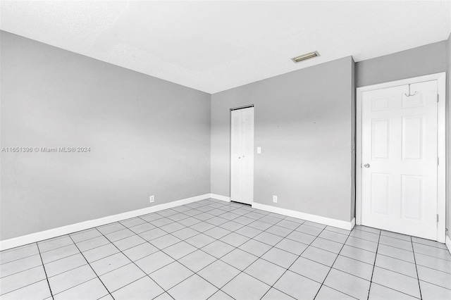 empty room featuring a textured ceiling and light tile patterned floors