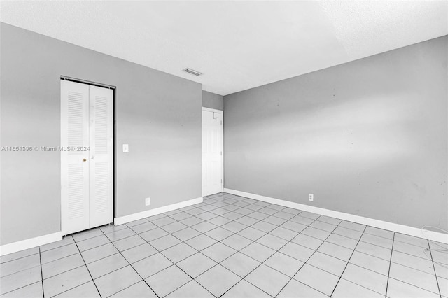 unfurnished room with a textured ceiling and light tile patterned flooring