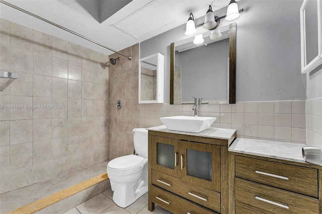 bathroom with vanity, backsplash, tiled shower, tile walls, and toilet