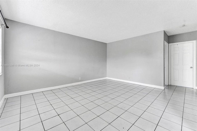 spare room featuring a textured ceiling and light tile patterned floors