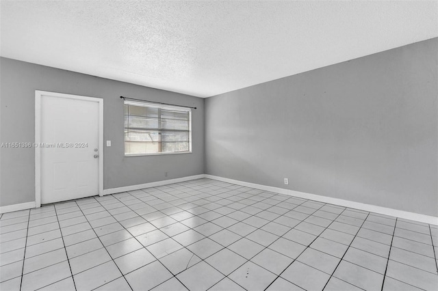 tiled empty room featuring a textured ceiling