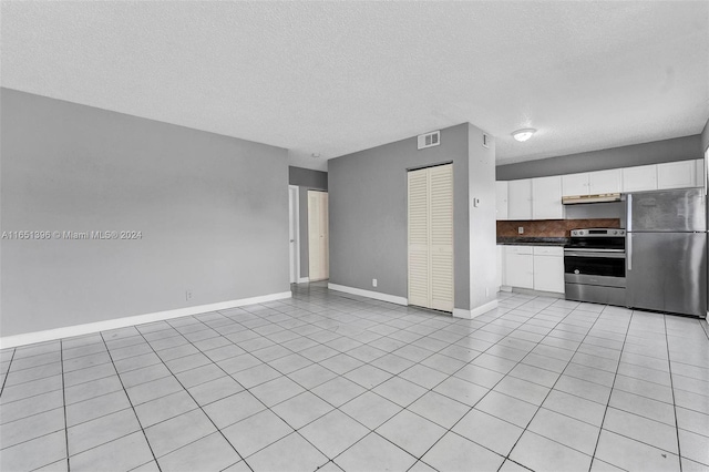 kitchen featuring white cabinetry, stainless steel appliances, light tile patterned flooring, and a textured ceiling