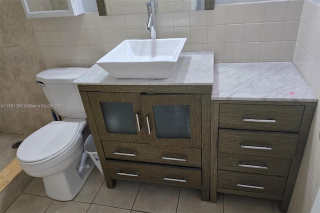 bathroom with tile walls, toilet, vanity, and tile patterned floors