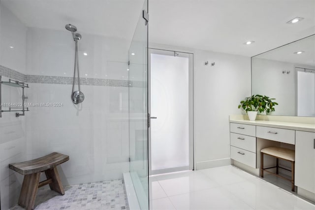 bathroom featuring vanity, a tile shower, and tile patterned flooring