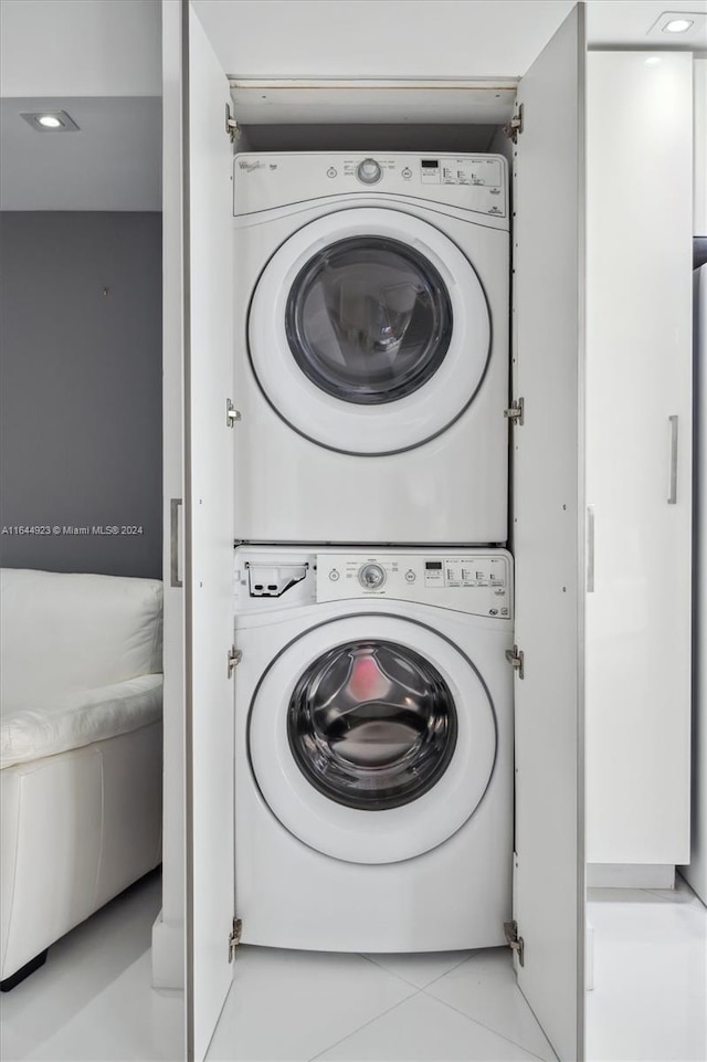 clothes washing area featuring light tile patterned floors and stacked washing maching and dryer