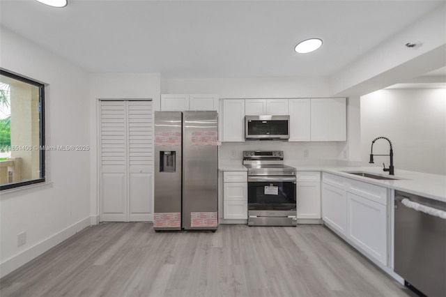 kitchen featuring white cabinets, stainless steel appliances, light hardwood / wood-style flooring, and sink