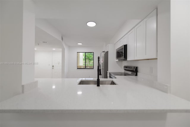 kitchen with sink, white cabinetry, kitchen peninsula, and stainless steel appliances