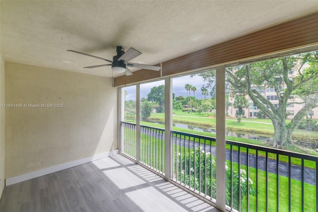 unfurnished sunroom featuring a water view and ceiling fan