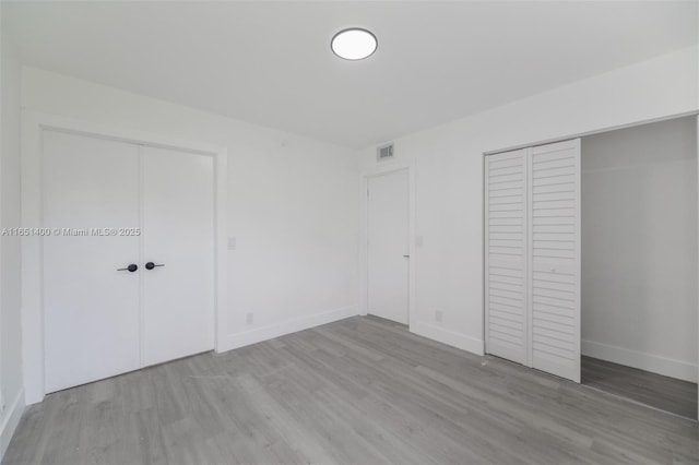 unfurnished bedroom with multiple closets and light hardwood / wood-style flooring