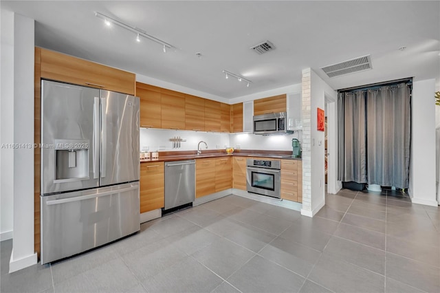 kitchen featuring light tile patterned floors, stainless steel appliances, light brown cabinets, and sink